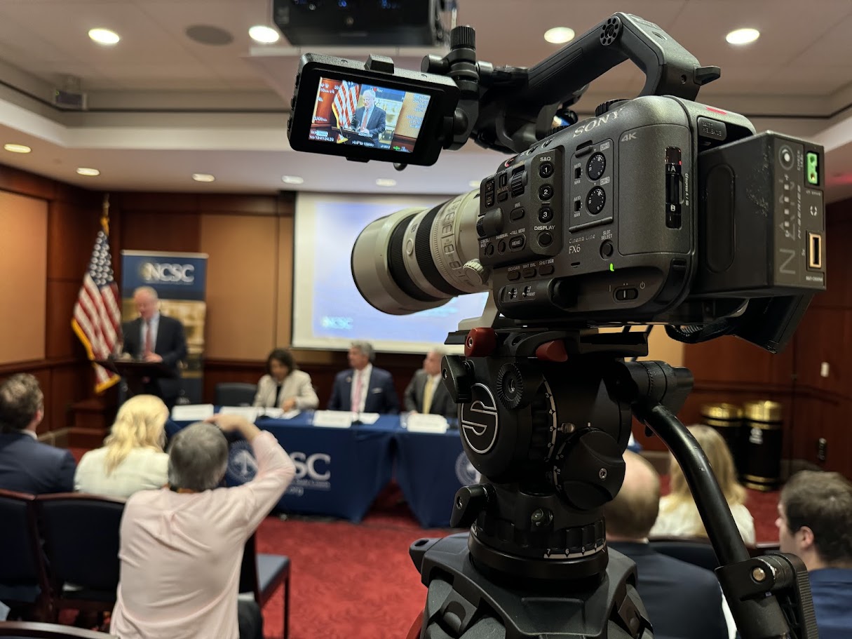 Cinema camera on a fluid-head tripod covering a panel session