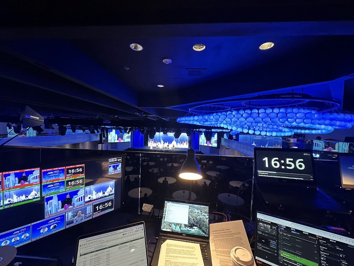 Front-of-house production control — multiviewer monitors, show clocks and cue scripts overlooking the ballroom