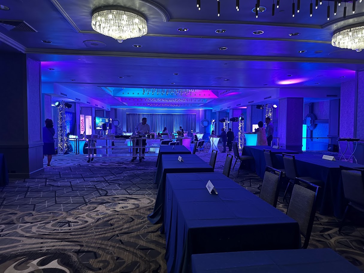Ballroom under blue and magenta uplighting with crystal chandeliers